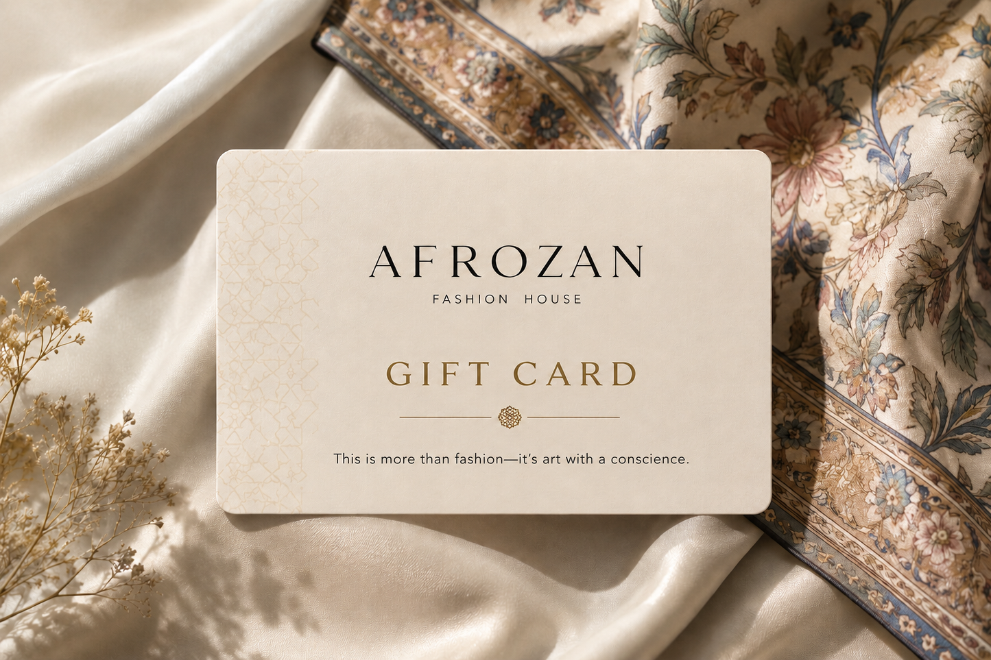 An Afrozan fashion house gift card with elegant black and gold lettering, styled on a draped cream silk fabric with a floral scarf in the background.